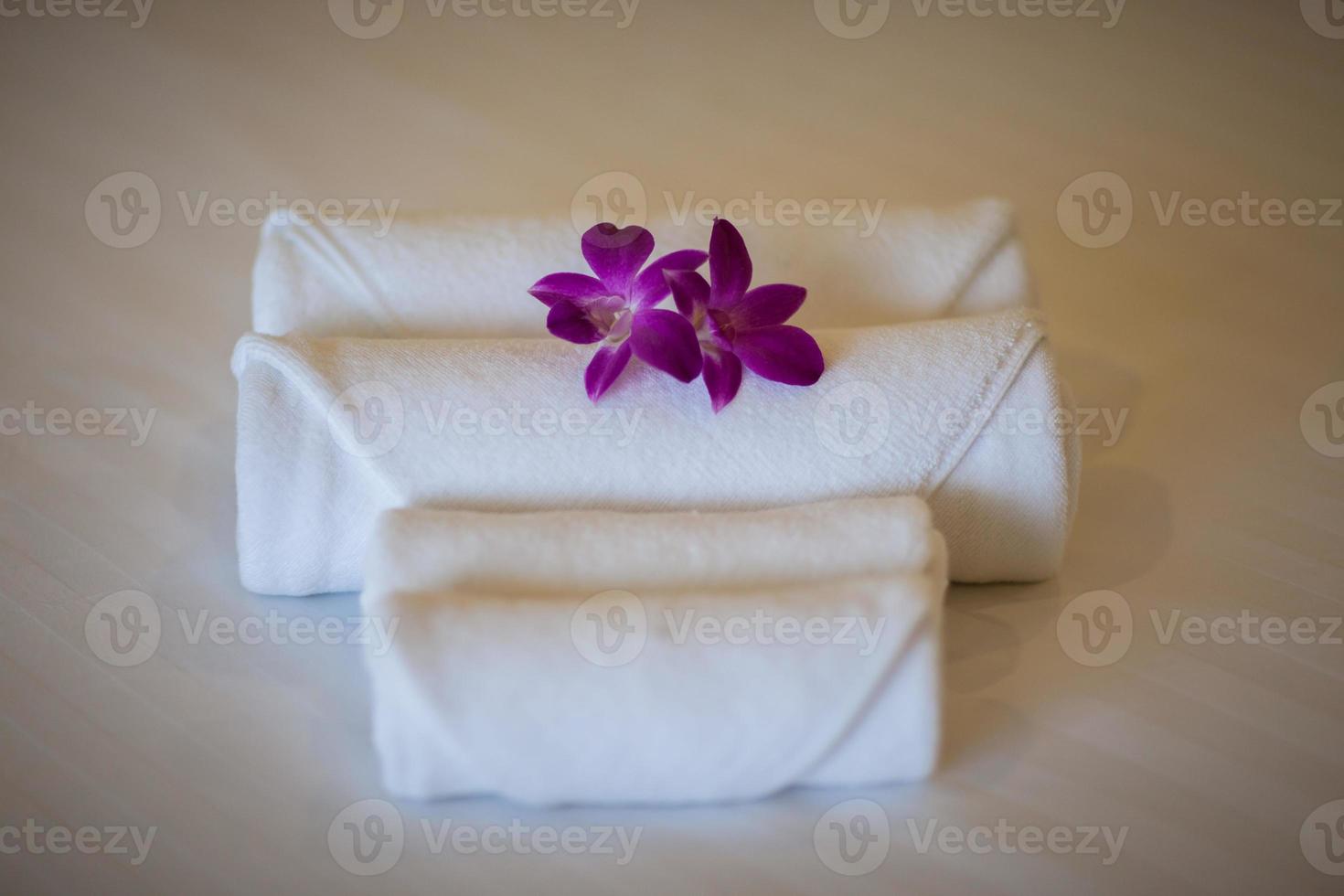 White towels on bed with purple flowers photo
