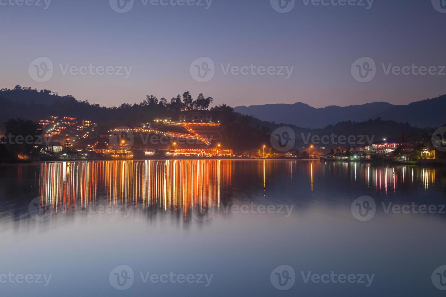 luces de la aldea reflejadas en el agua por la noche foto