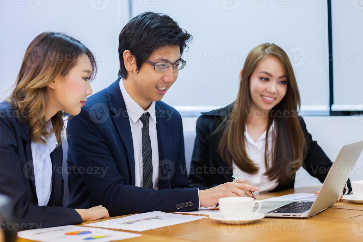 Three coworkers looking at a laptop photo