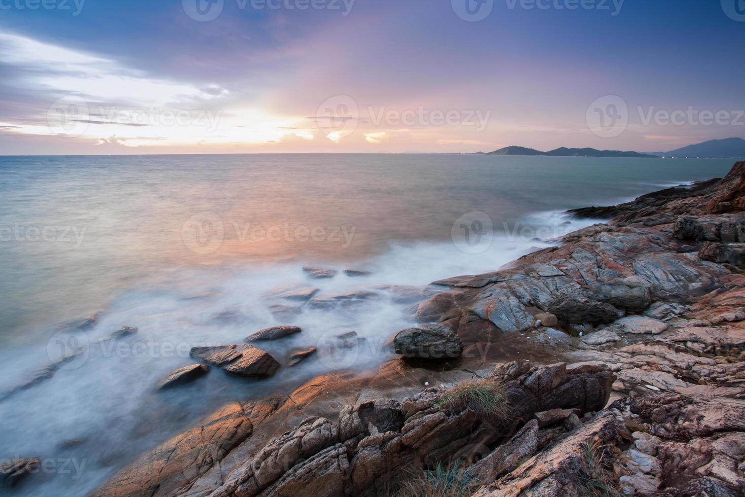 Long-exposure of beach waves on rocks photo