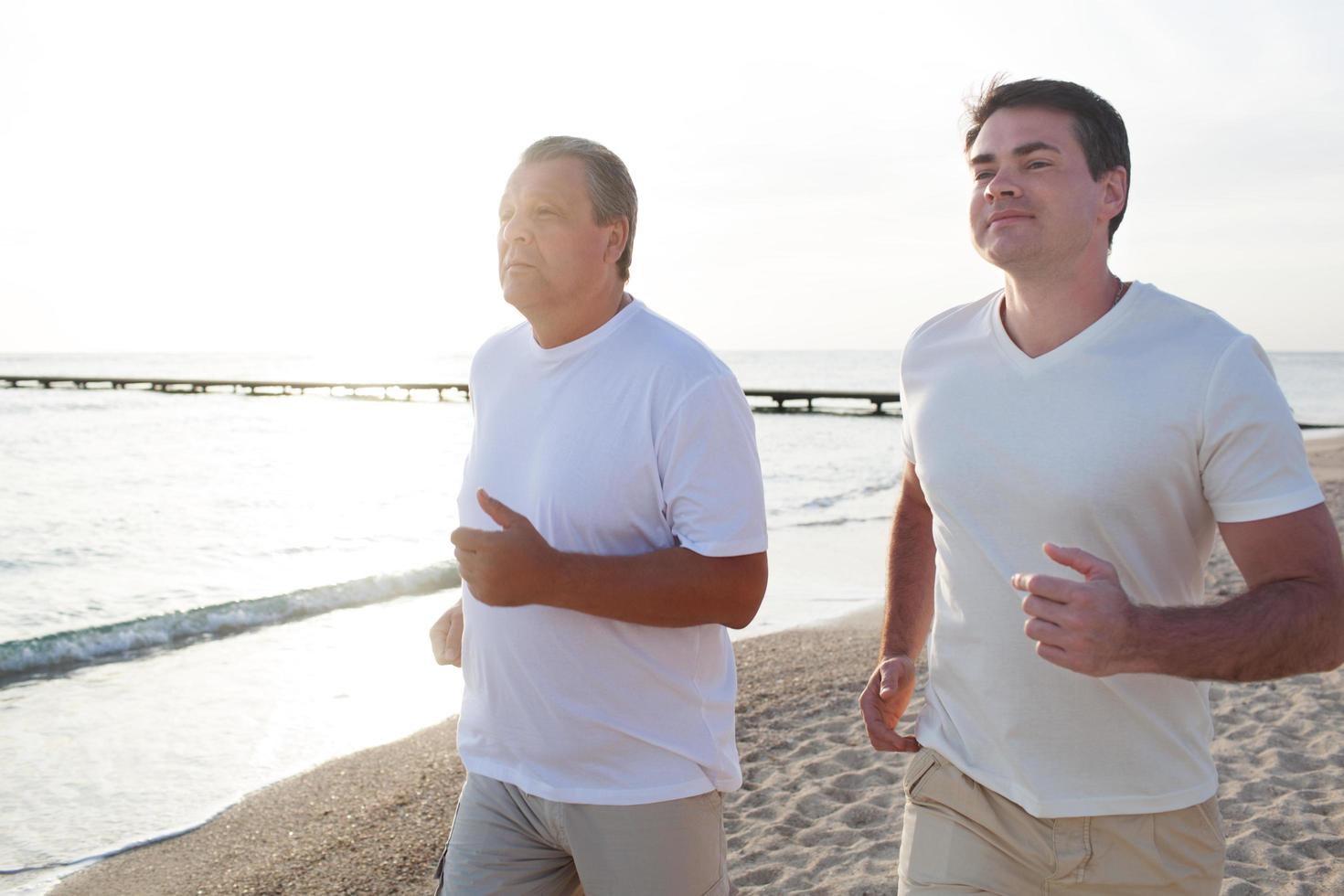 Two men running along the coast in bright sunlight photo