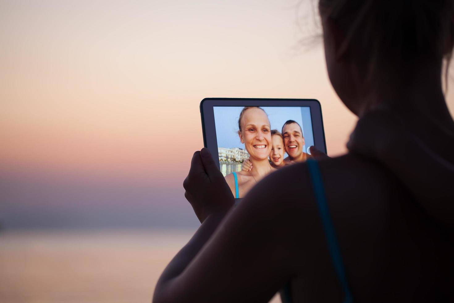 Family virtually connecting on a beach photo