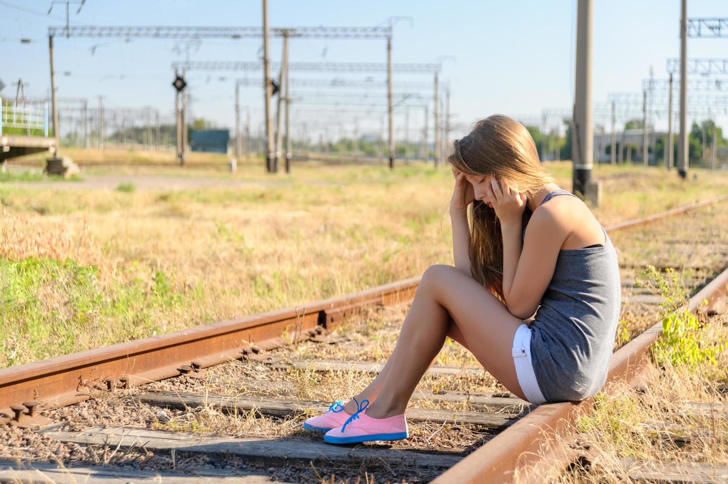 Sad girl sitting on a train tracks photo