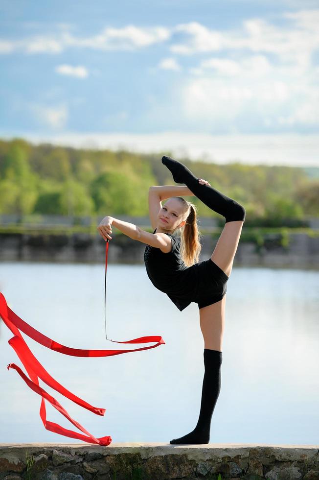 Rhythmic gymnast in a vertical split with a ribbon photo