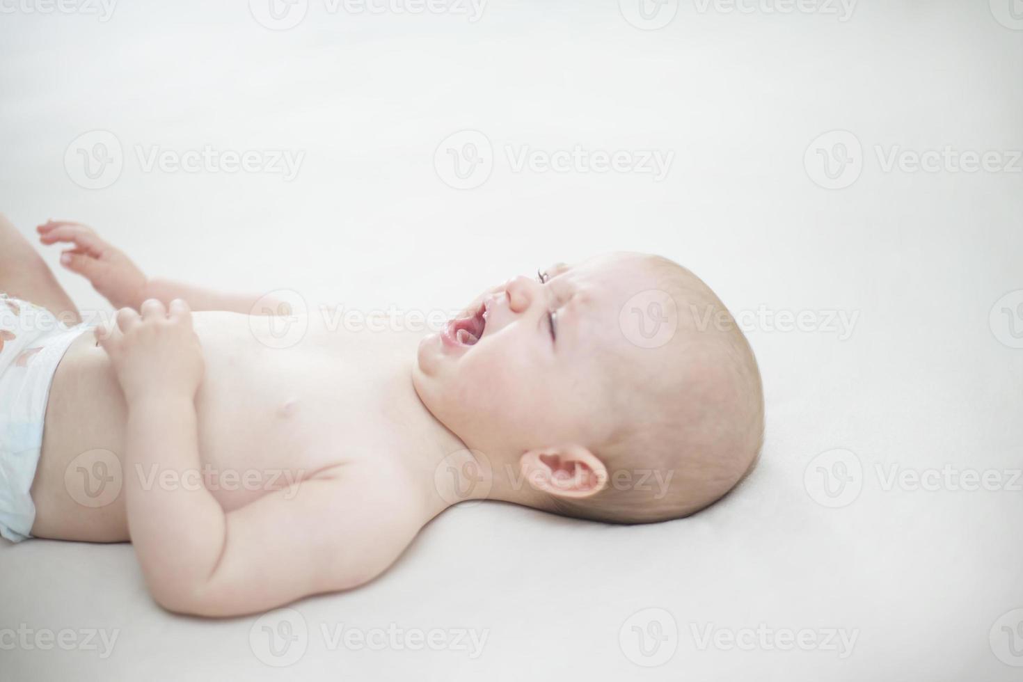 Cute baby girl crying on bed photo