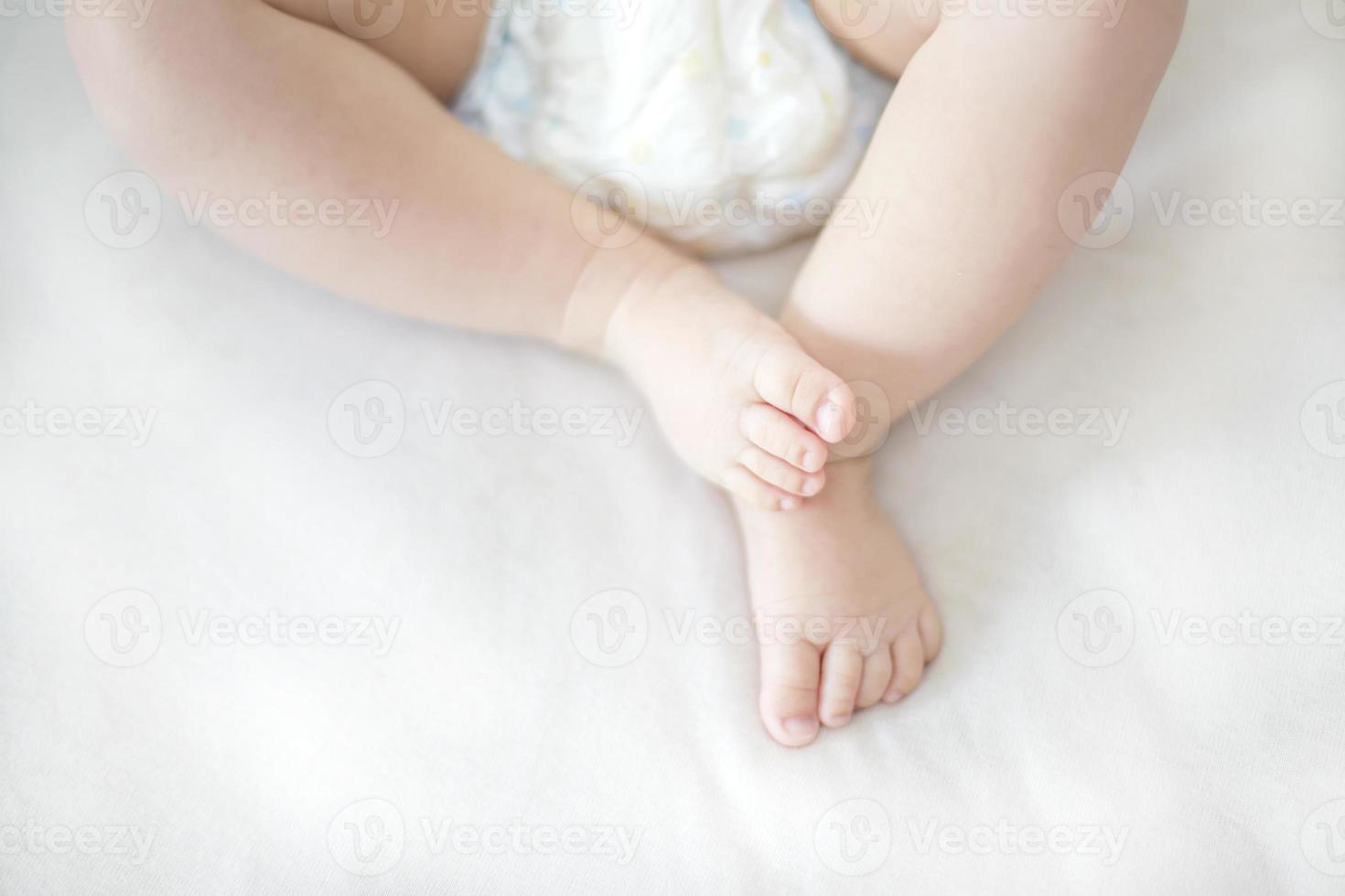 pequeños pies de niña en la cama foto