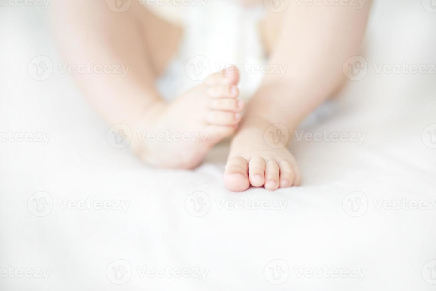 pequeños pies de niña en la cama foto