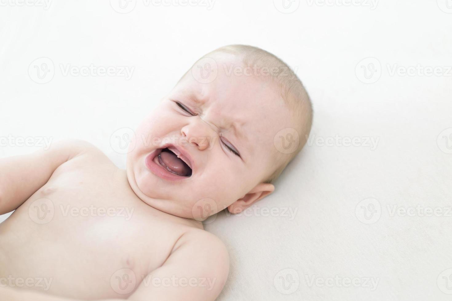Cute baby girl crying on bed photo