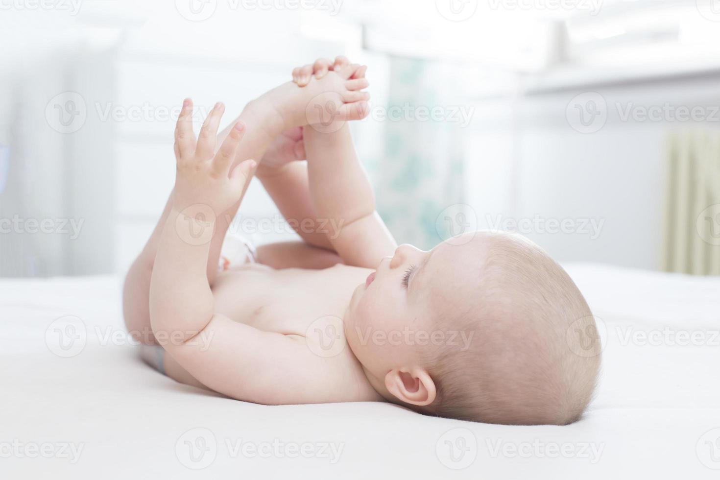 niña acostada y metiéndose la pierna en la boca foto