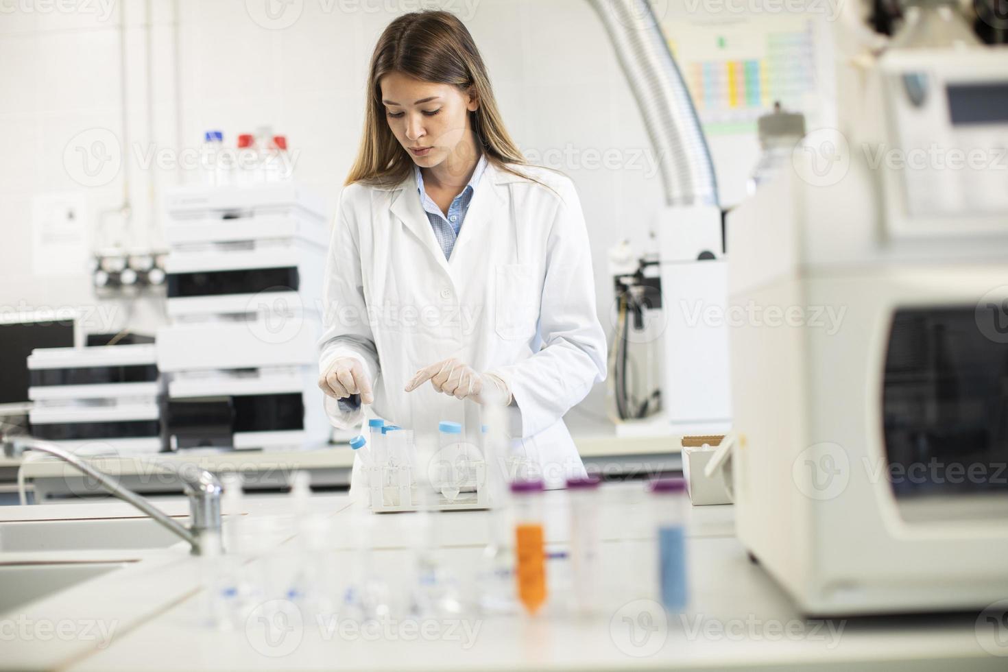 Doctora con mascarilla protectora en el laboratorio con matraz con muestra de líquido foto