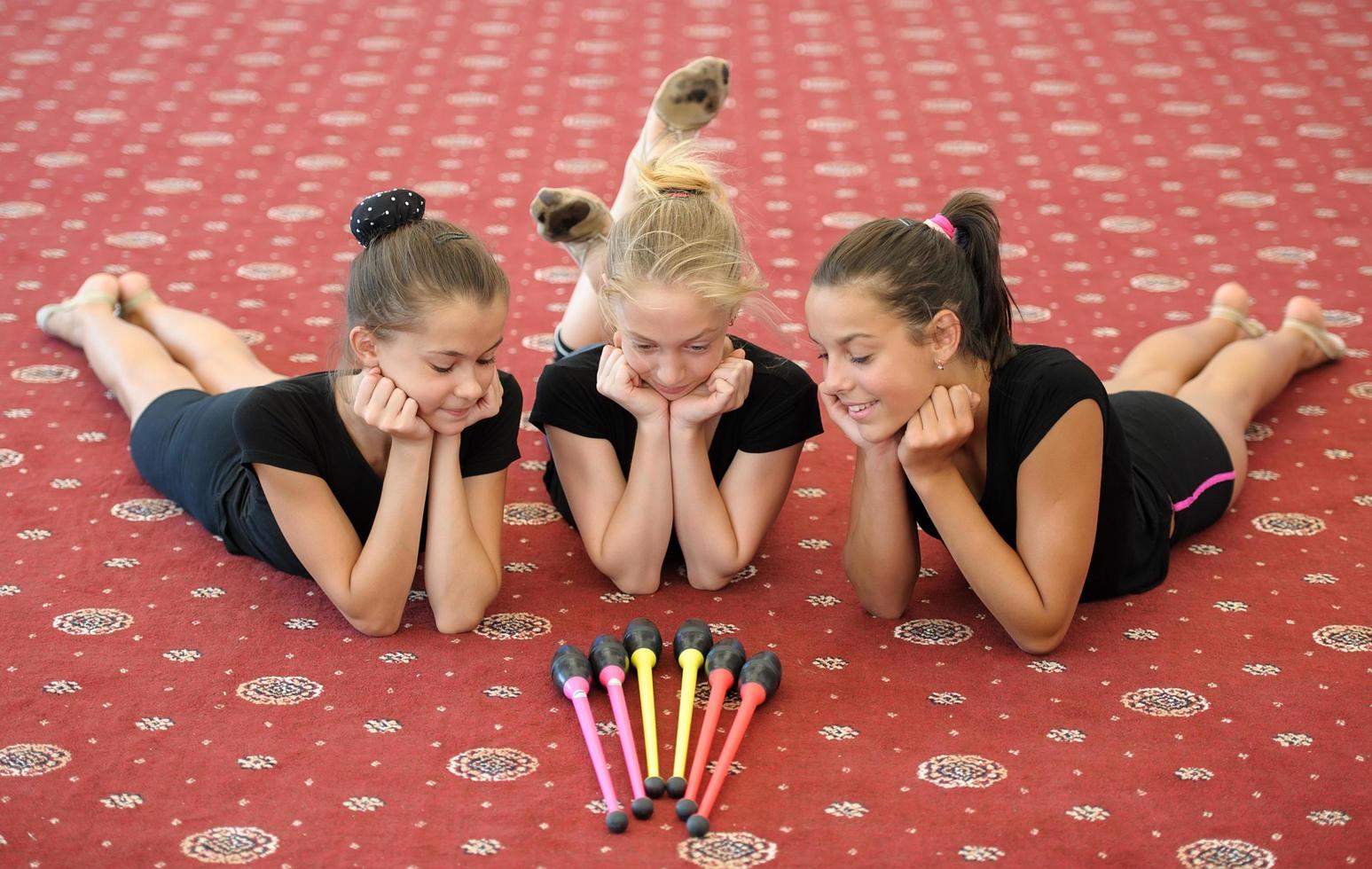 Three girls on the floor looking at gymnastic sticks photo