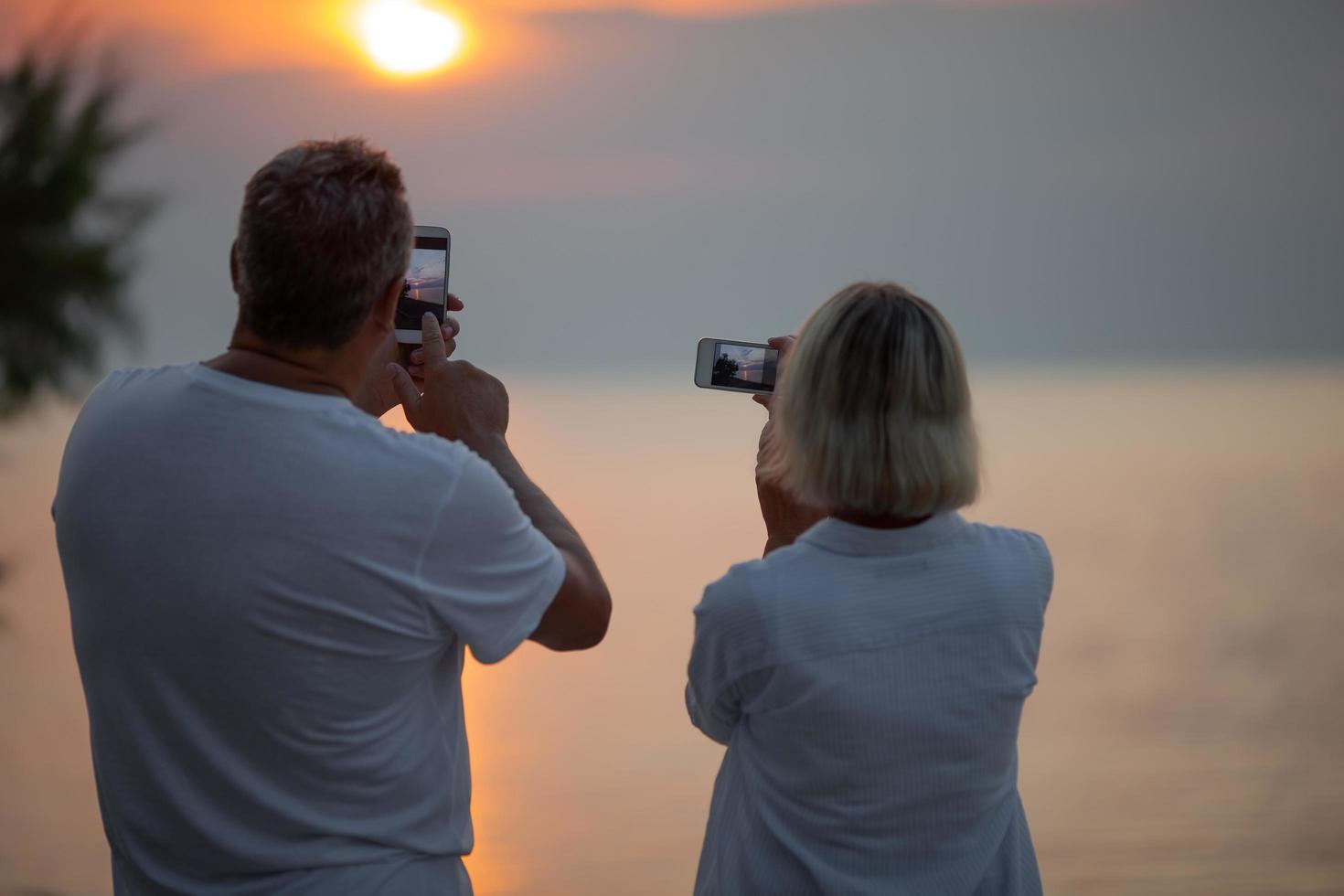 pareja tomando fotos de una puesta de sol