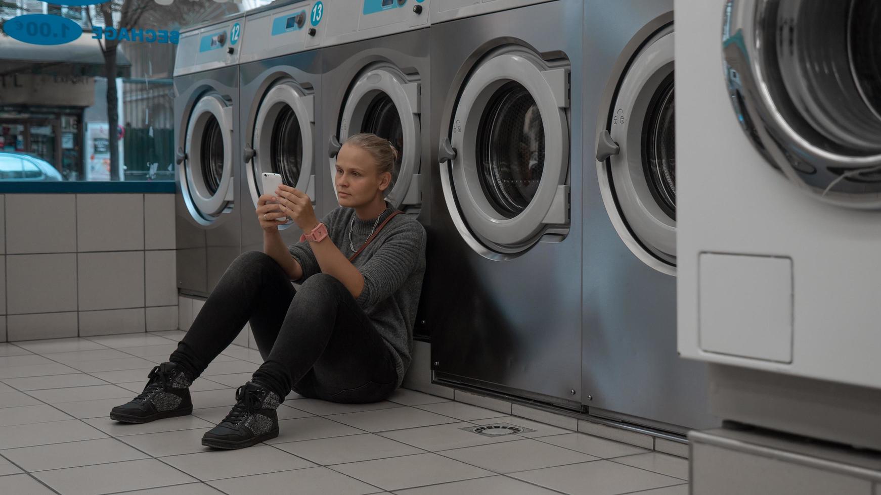 Woman on her phone at a laundromat photo