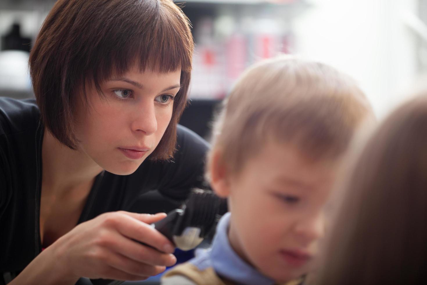 Hairstylist cutting a young boy's hair photo