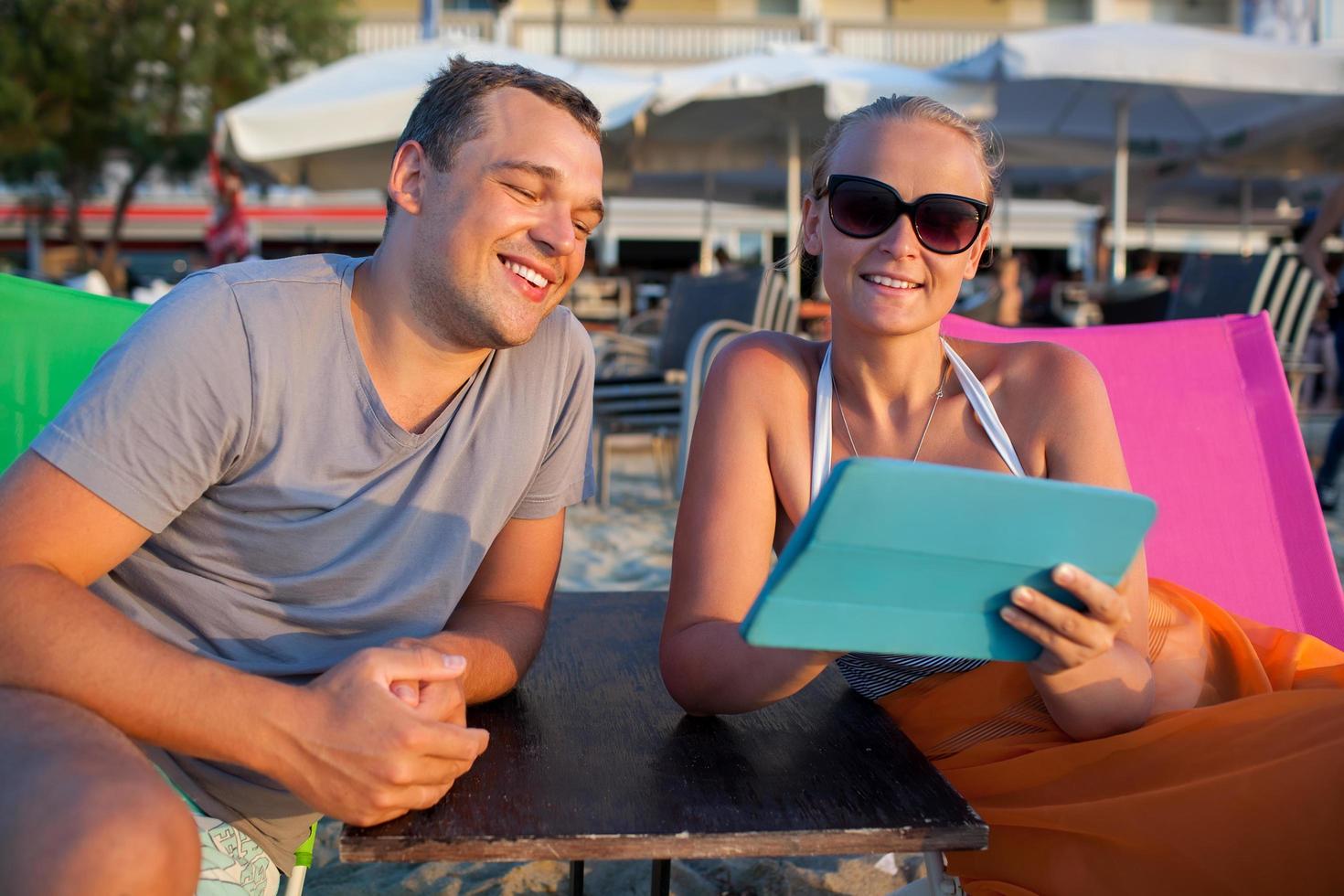 Man and woman on a beach with a tablet photo