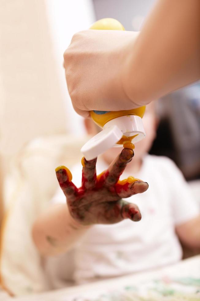 padre aplicando pintura a la mano de un niño foto