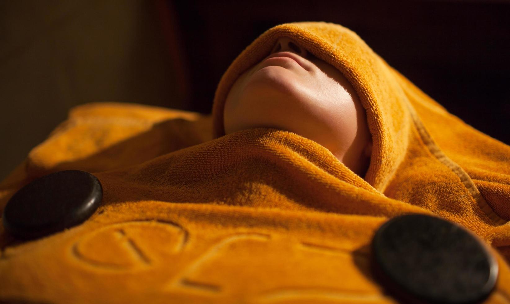 Woman getting a hot towel treatment at beauty spa photo