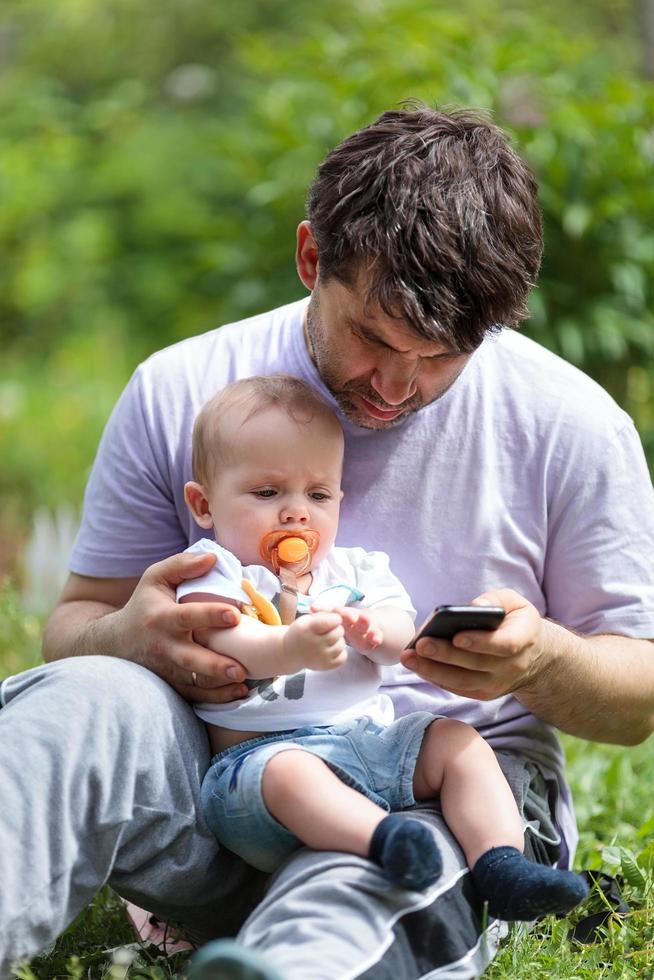 Father holding child while on phone photo