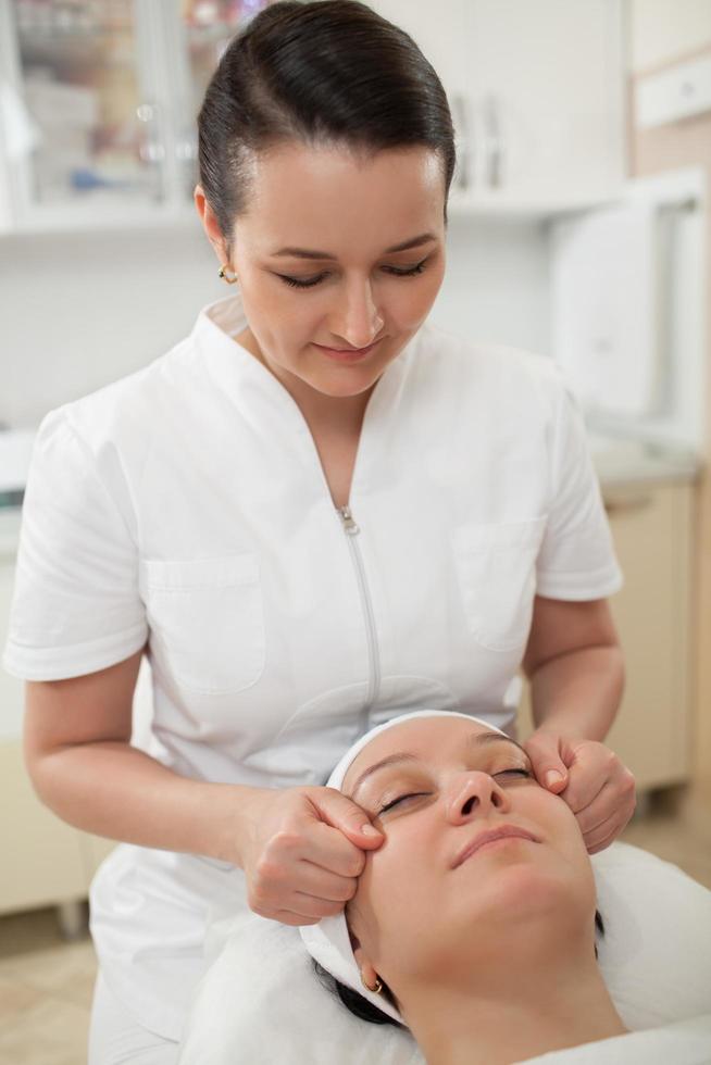 mujer recibiendo un masaje facial en un spa de belleza foto