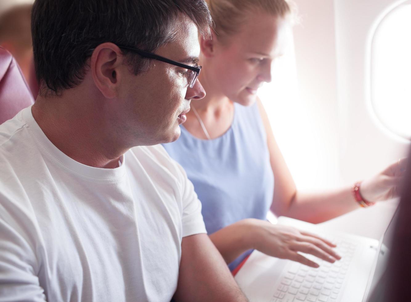 Couple using a laptop on a plane photo