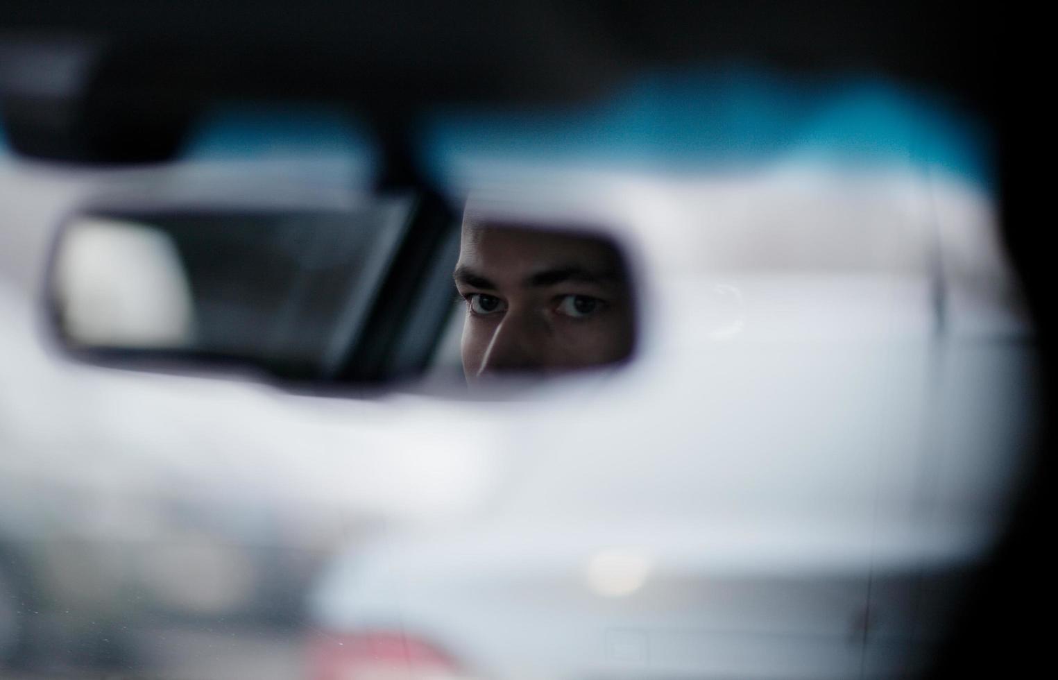 Man looking in the rearview mirror while driving photo