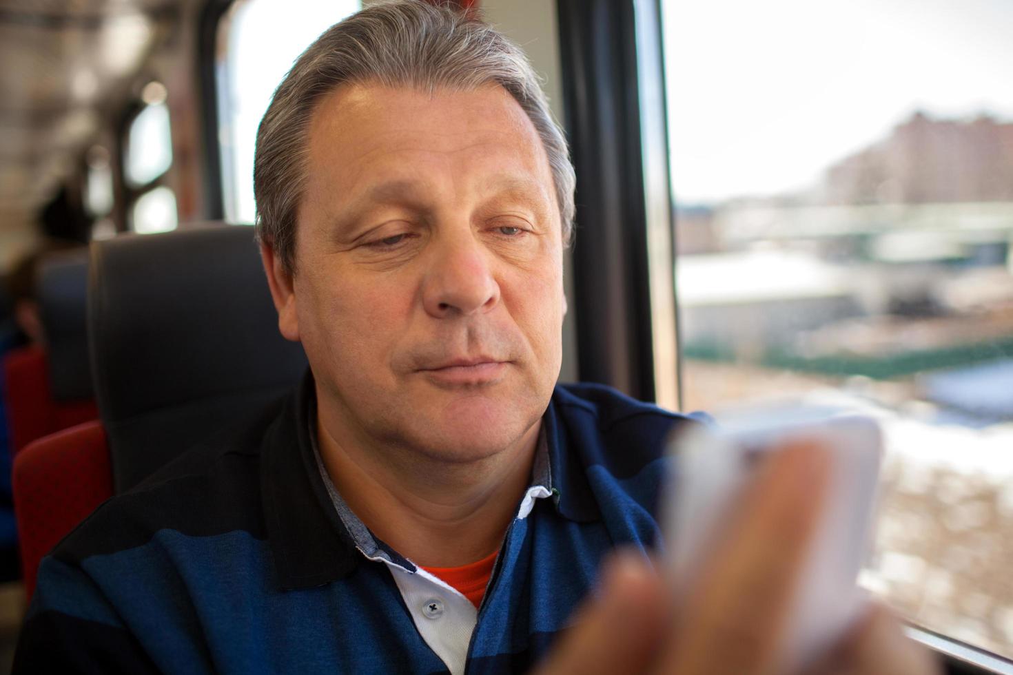 Hombre usando un teléfono móvil durante un viaje en tren foto