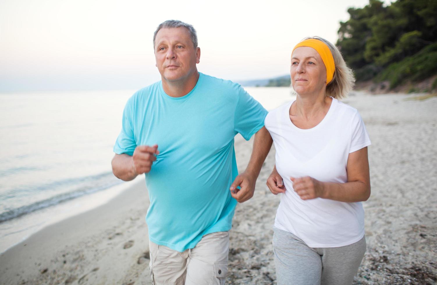 Senior couple jogging on the beach photo