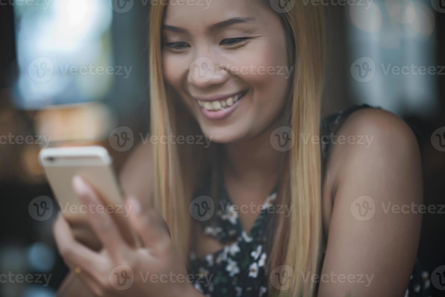 Mujeres jóvenes usando y mirando el teléfono inteligente en la cafetería de la ventana foto