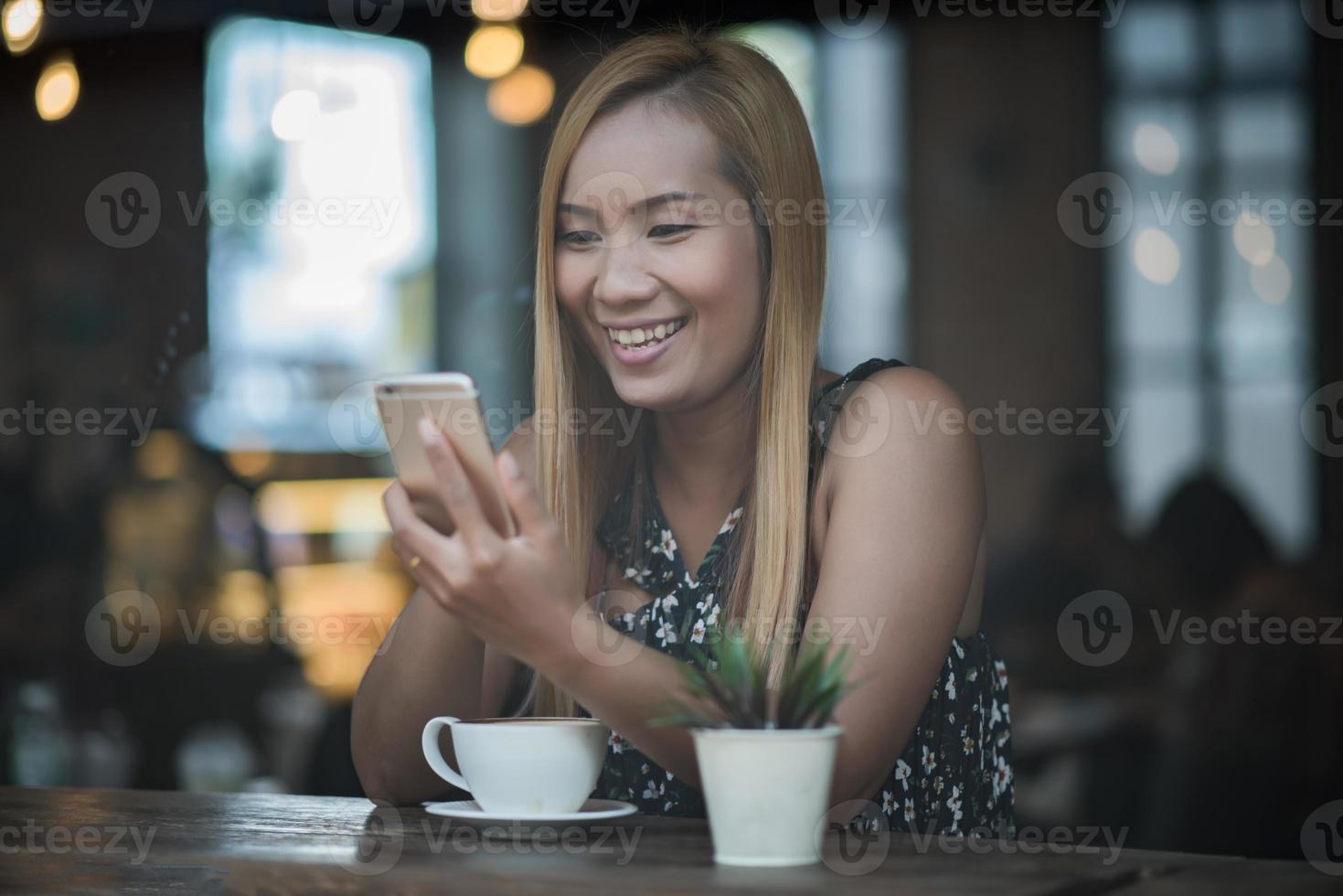 Mujeres jóvenes usando y mirando el teléfono inteligente en la cafetería de la ventana foto