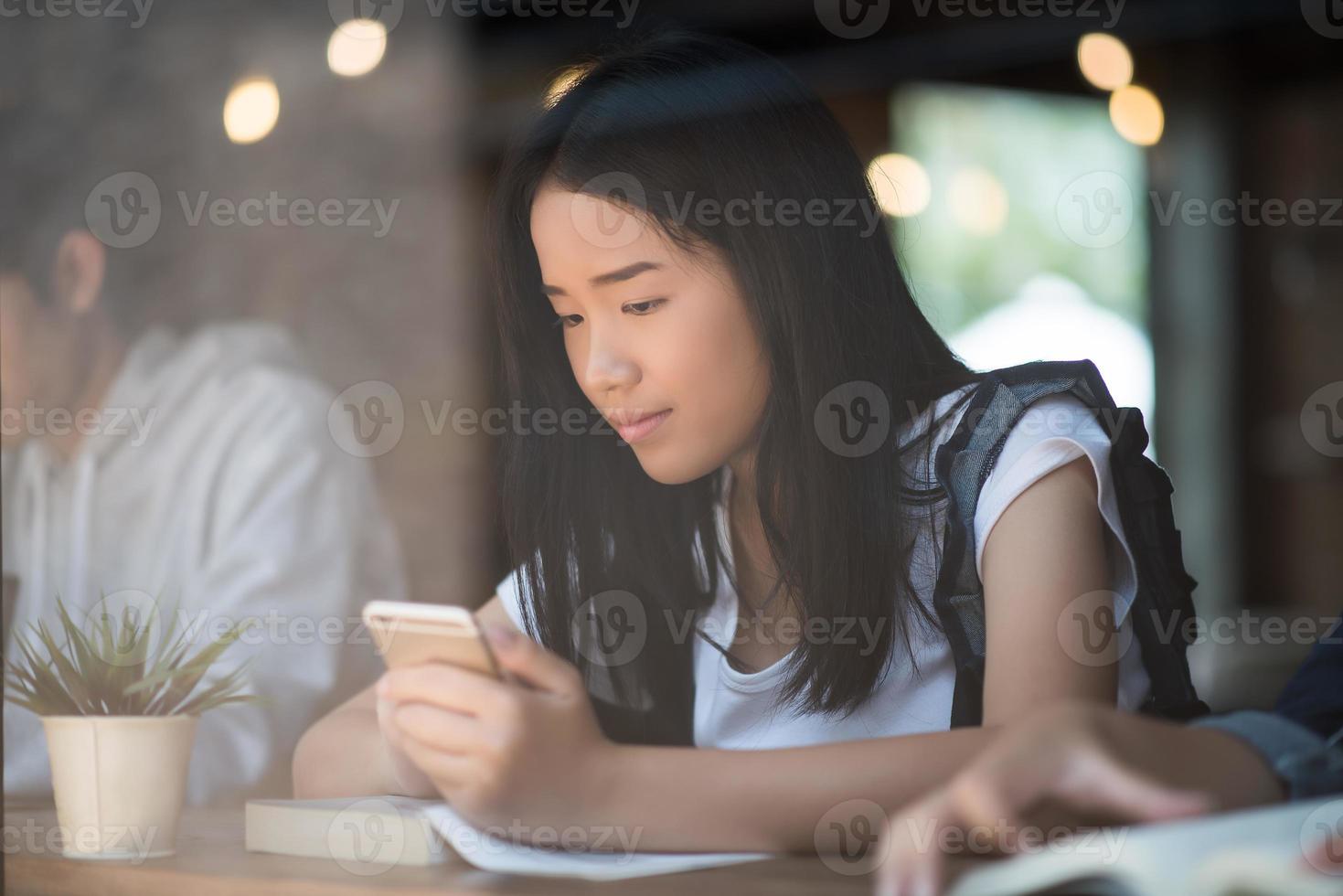 Mujeres jóvenes usando y mirando el teléfono inteligente en la cafetería de la ventana foto