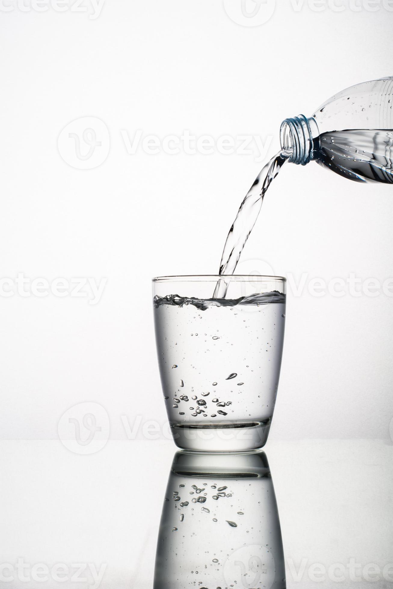 Close-up of pouring water into glass isolated on white background