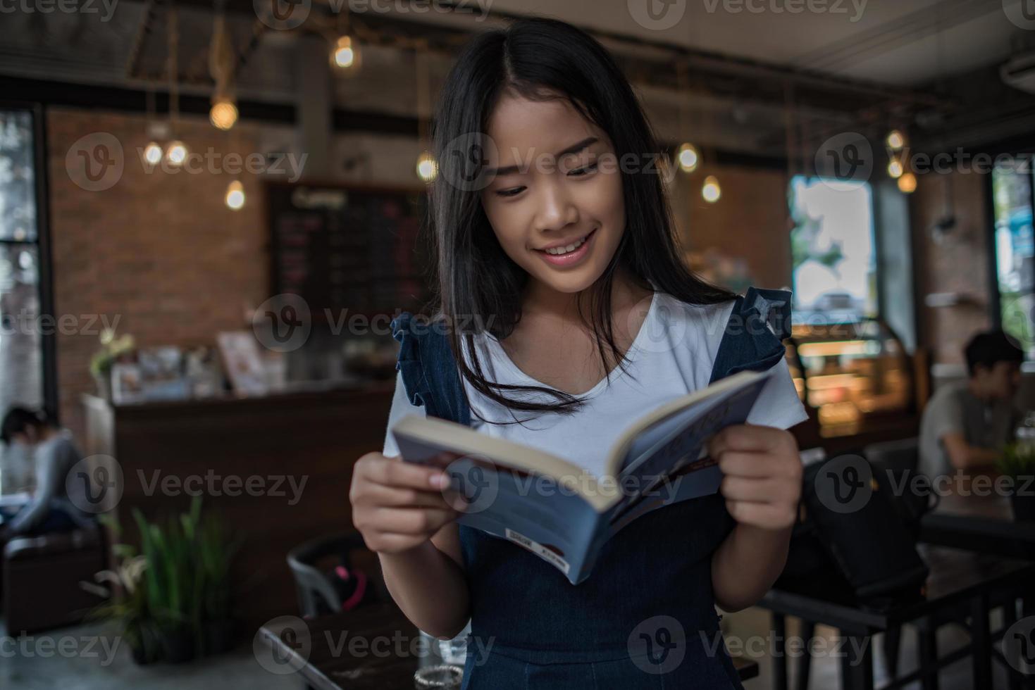 mujer joven, libro de lectura, sentado, adentro, en, urbano, café foto