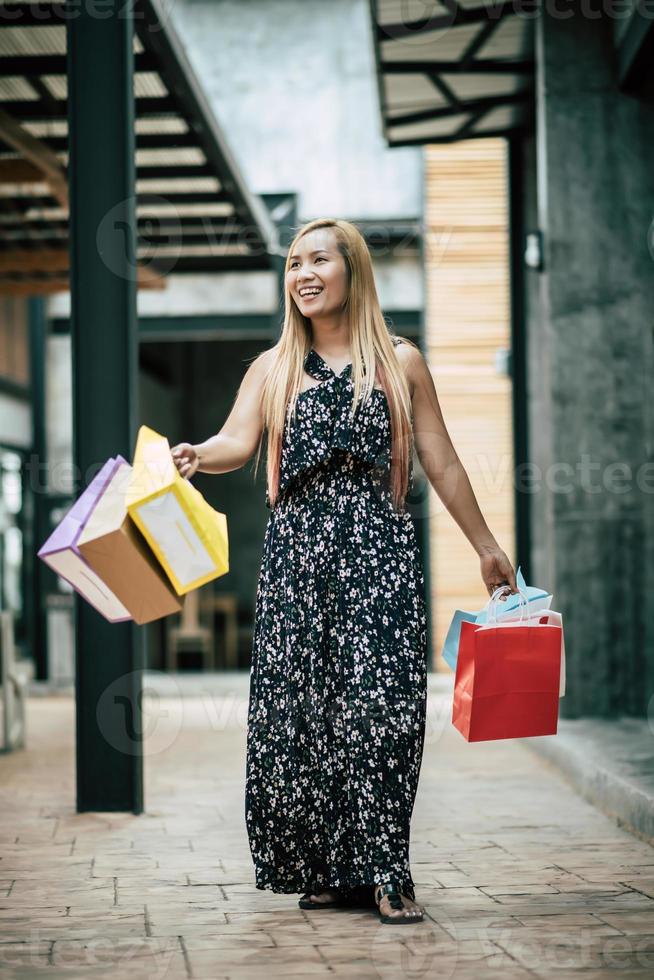 retrato, de, un, joven, mujer feliz, con, bolsas de compras, ambulante, en la calle foto