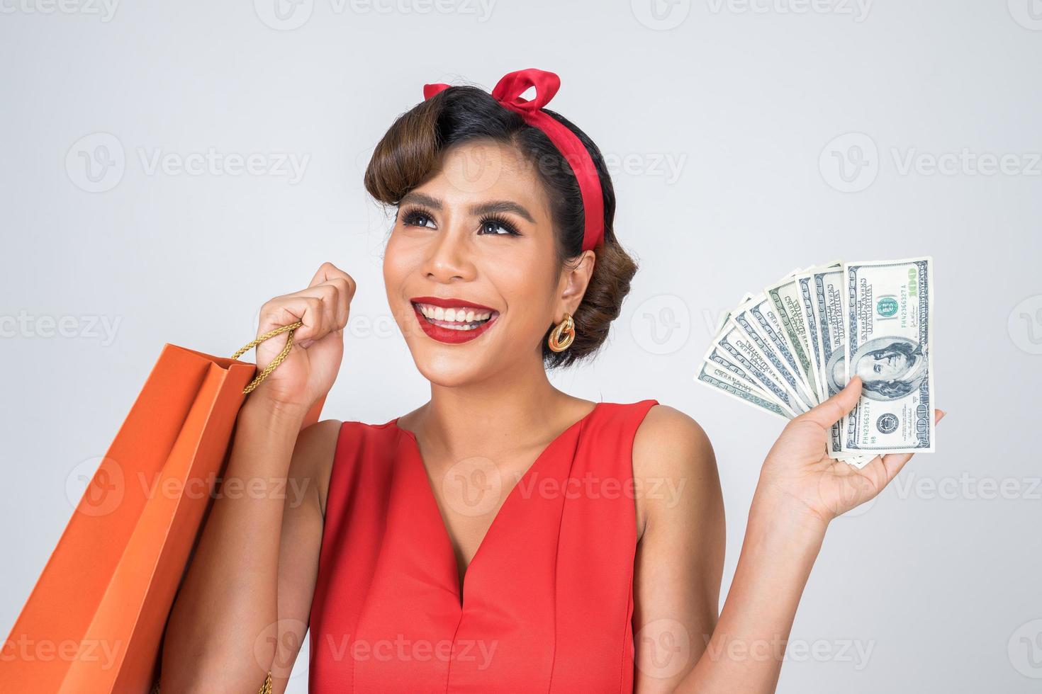 Beautiful Asian woman holding colored shopping bags and money photo