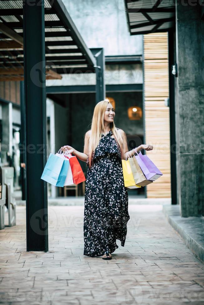 retrato, de, un, joven, mujer feliz, con, bolsas de compras, ambulante, en la calle foto