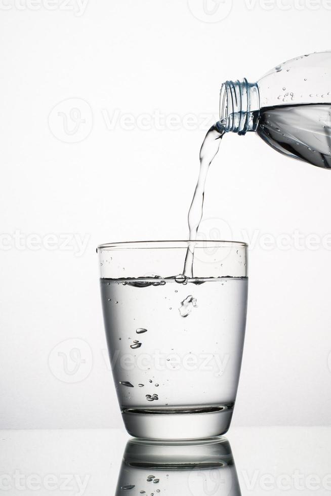 Close-up de verter agua en un vaso aislado sobre fondo blanco. foto