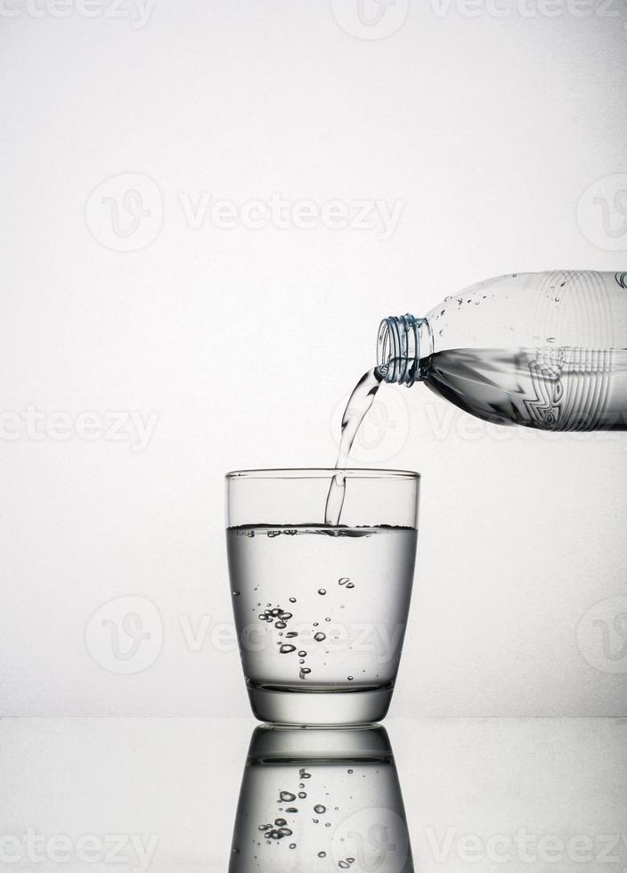 Close-up de verter agua en un vaso aislado sobre fondo blanco. foto