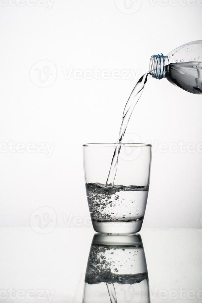 Close-up de verter agua en un vaso aislado sobre fondo blanco. foto
