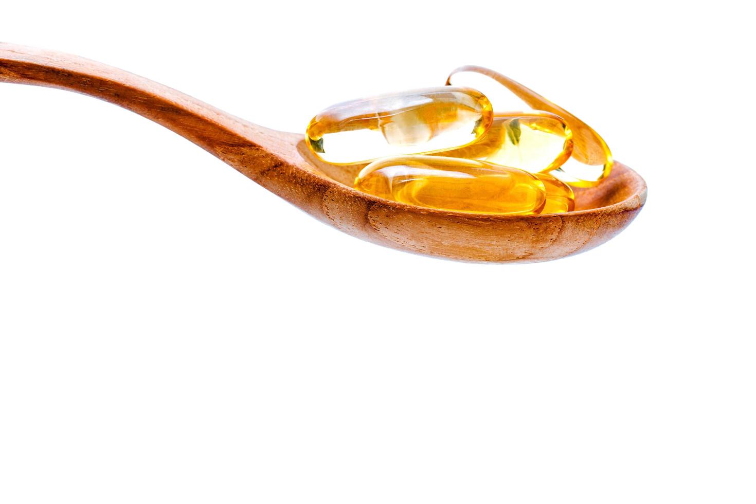 Fish oil pills on a wooden spoon photo
