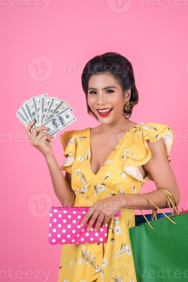 Young fashionable woman holding a wallet with cash and shopping bags photo