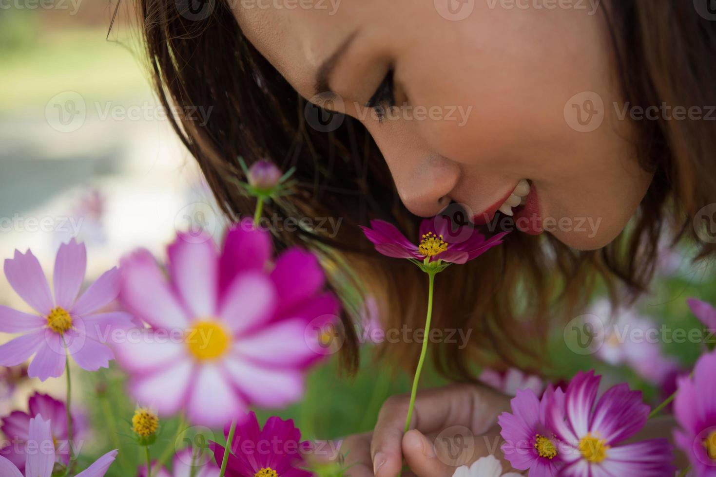 Close-up of cheerful woman smelling cosmos flowers in a garden photo