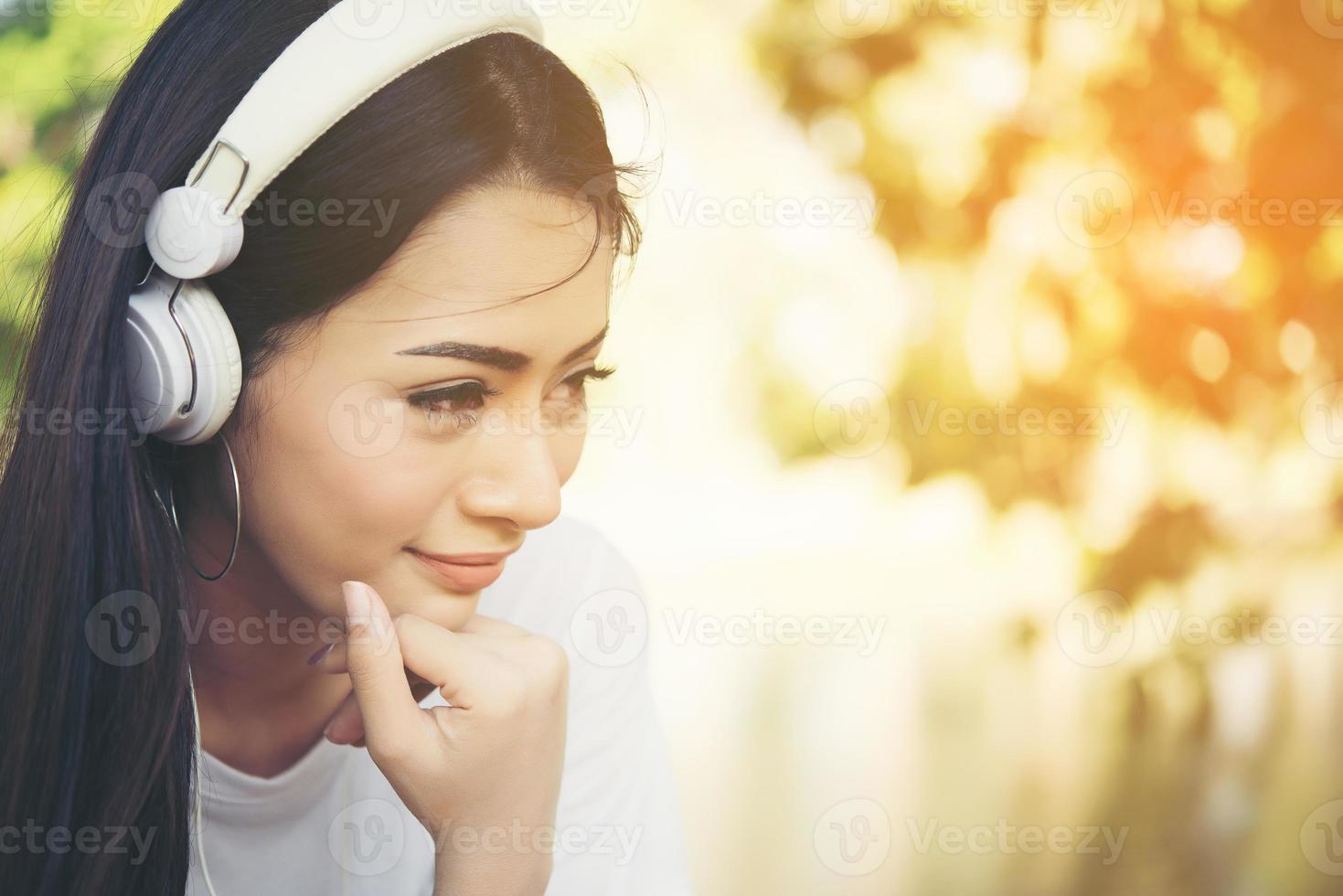 Retrato de una niña sonriente con auriculares escuchando música en la naturaleza foto