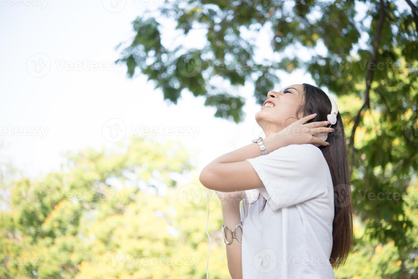 Retrato de una niña sonriente con auriculares escuchando música en la naturaleza foto