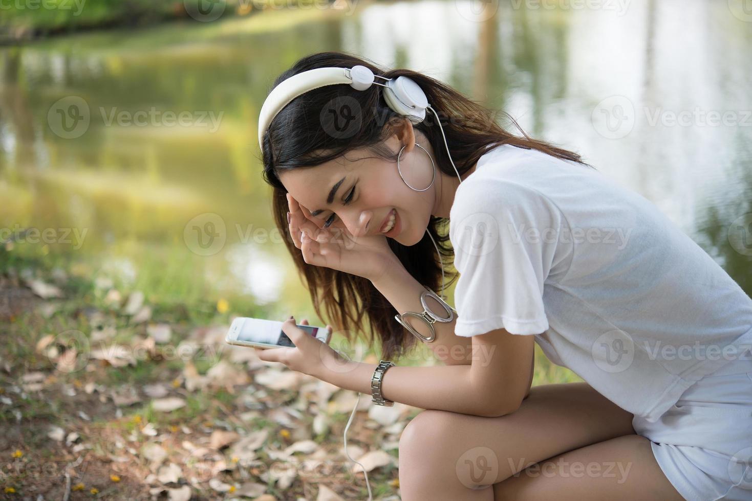 Retrato de una niña sonriente con auriculares escuchando música en la naturaleza foto