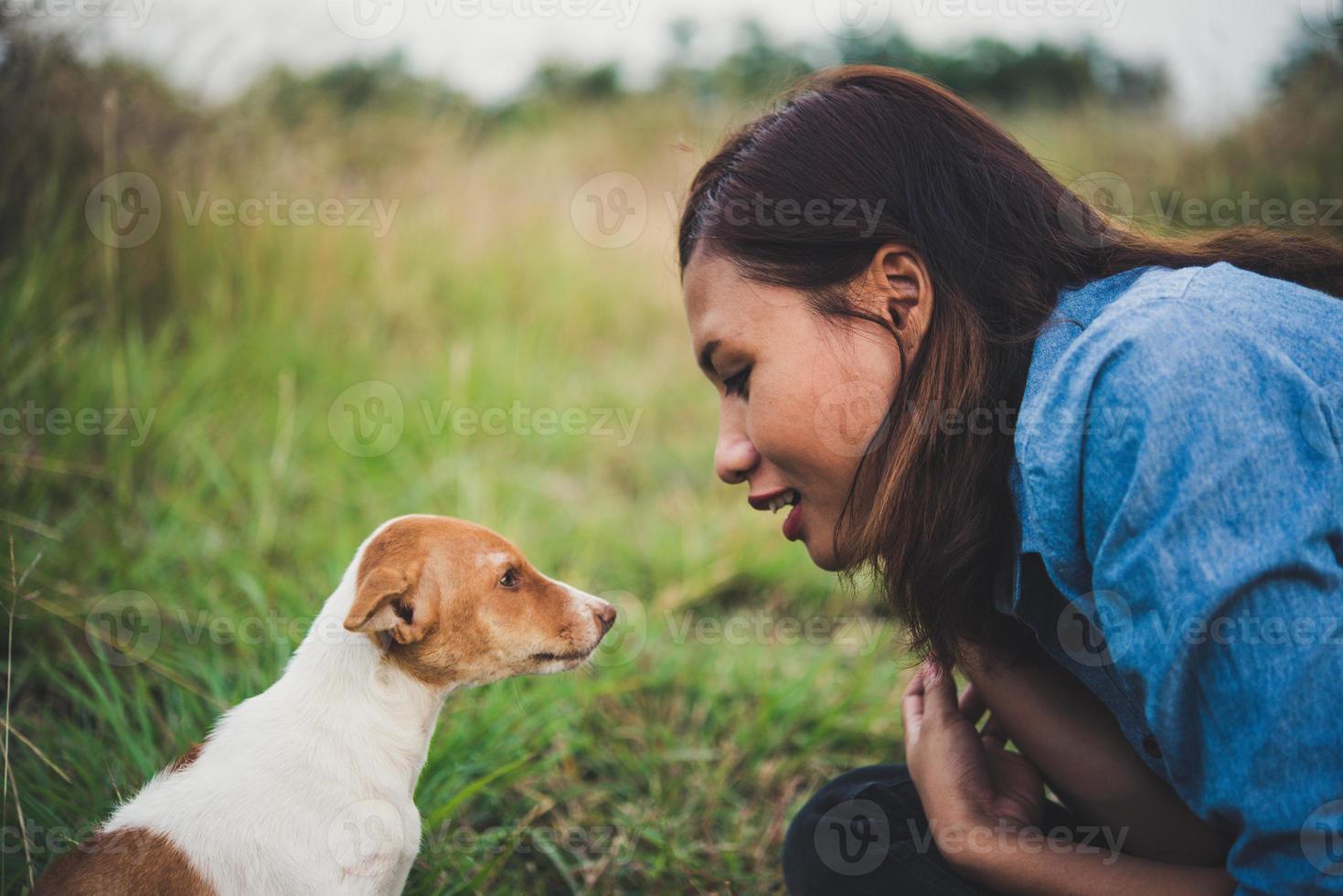 Happy cheerful hipster girl playing with her dog in the park during sunset photo