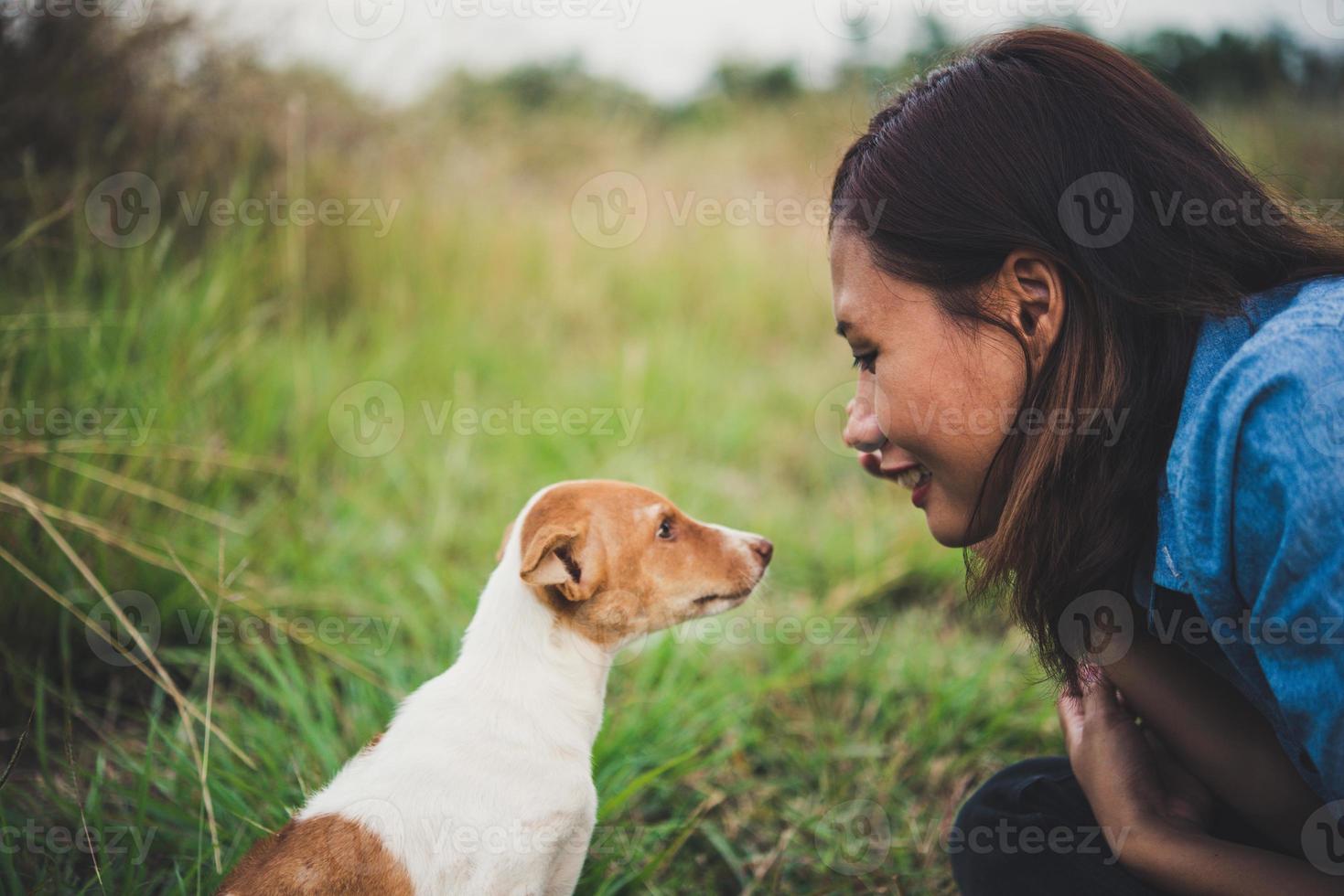 Happy cheerful hipster girl playing with her dog in the park during sunset photo