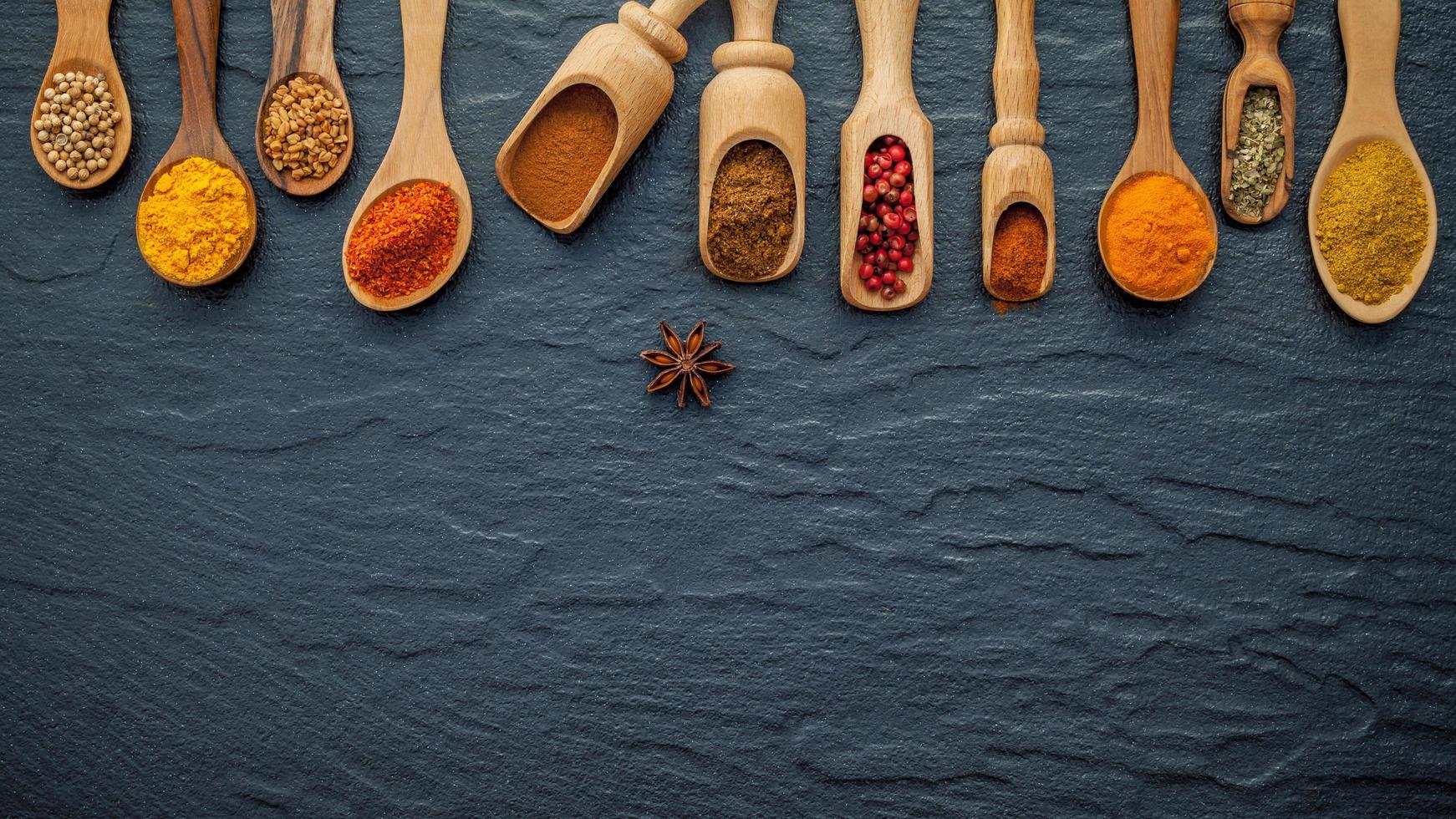 Various spices and herbs in wooden spoons with copy space photo