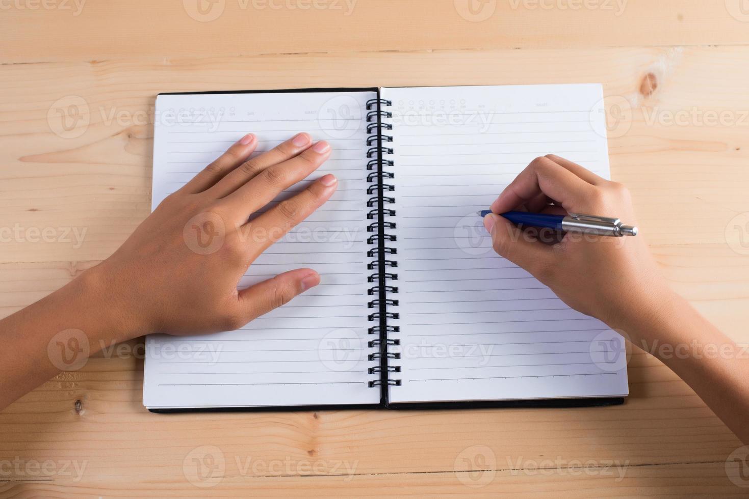 Vista superior de la mano de mujer escribiendo en el bloc de notas foto