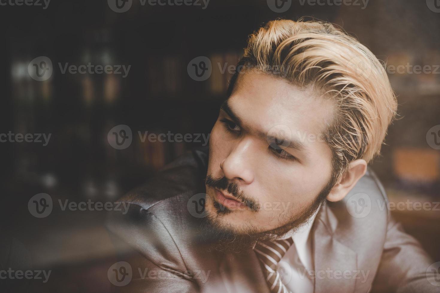 Young businessman sitting at cafe bar, looking away and thinking photo