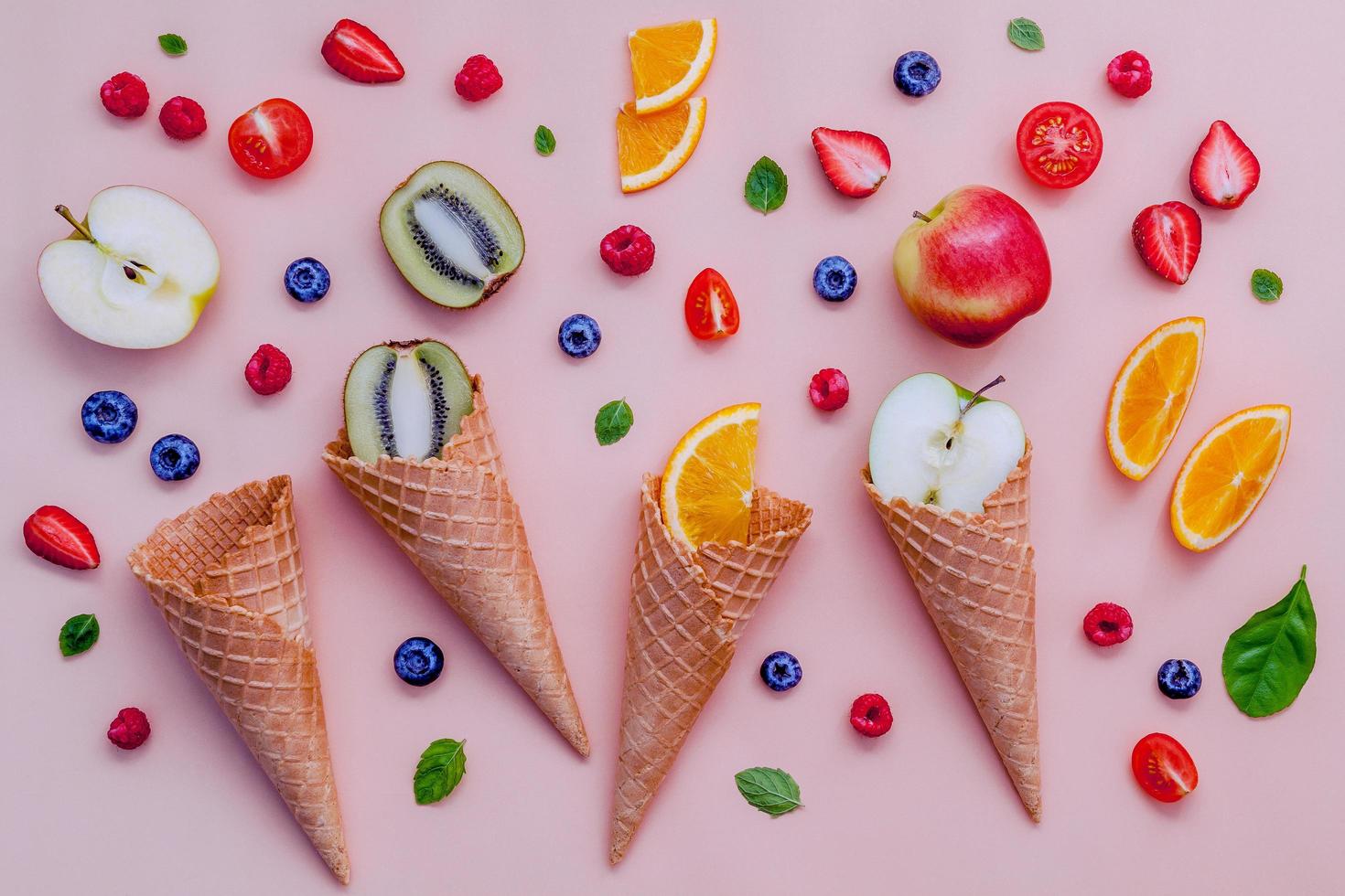 Conos de helado y frutas sobre un fondo rosa. foto